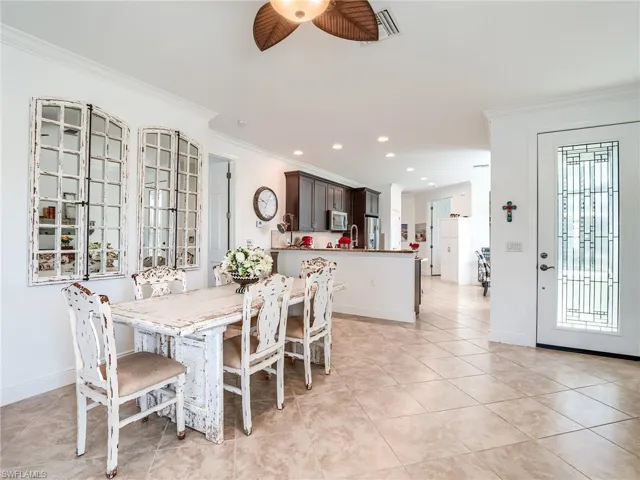 Tiled dining space featuring sink, ornamental molding, plenty of natural light, and ceiling fan