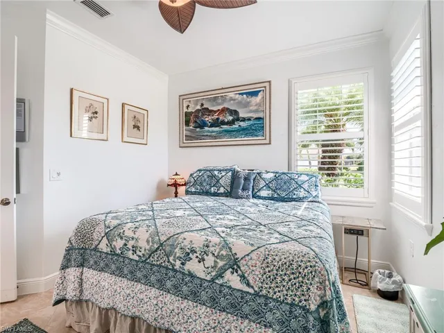 Tiled bedroom with ceiling fan and crown molding