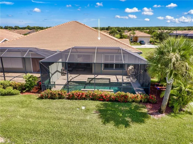 Rear view of house featuring a patio, glass enclosure, and a yard