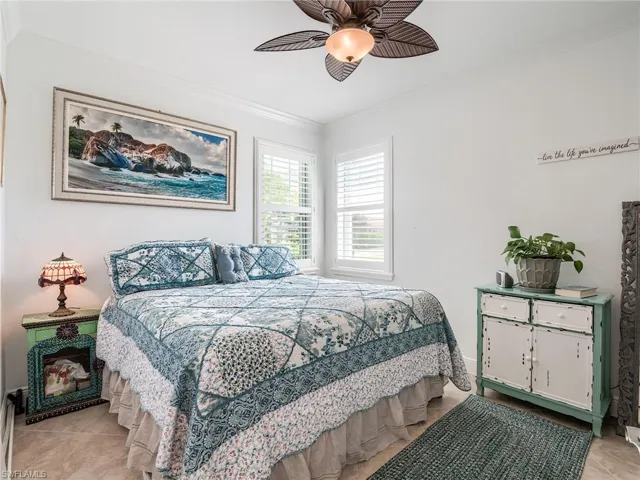 Tiled bedroom featuring ceiling fan and ornamental molding