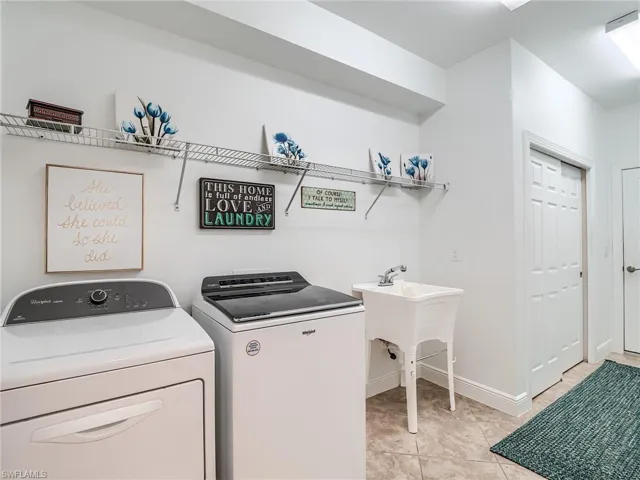 Laundry room with independent washer and dryer, sink, and light tile flooring