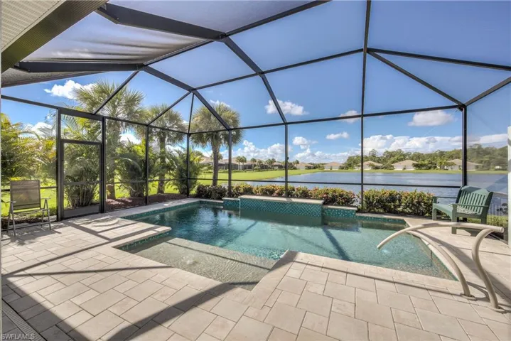 View of swimming pool with glass enclosure, a water view, and a patio area