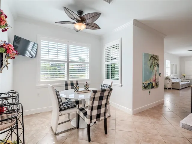 Tiled dining space featuring ornamental molding and ceiling fan