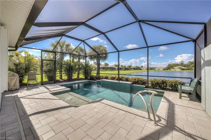View of pool with a patio, glass enclosure, and a water view