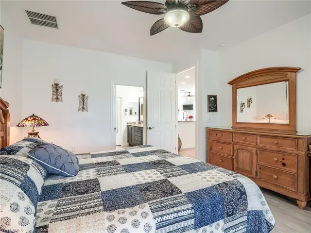 Bedroom with ceiling fan, ensuite bathroom, and light hardwood / wood-style flooring
