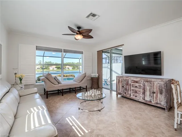 Living room with ceiling fan, crown molding, and light tile floors