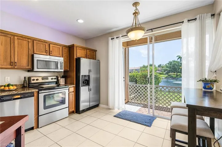 Kitchen featuring appliances with stainless steel finishes, brown cabinetry, hanging light fixtures, light tile patterned floors, and recessed lighting