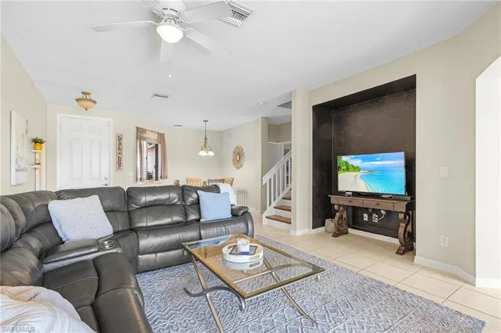 Living area with light tile patterned flooring, stairs, a ceiling fan, and baseboards