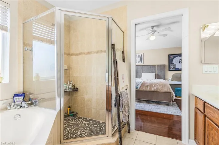 Bathroom featuring ensuite bath, a stall shower, a ceiling fan, vanity, and tile patterned flooring