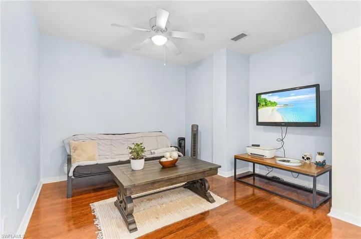Living area with wood finished floors, a ceiling fan, arched walkways, and baseboards