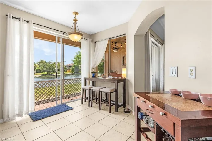 Dining room featuring light tile patterned floors, a water view, arched walkways, and a ceiling fan