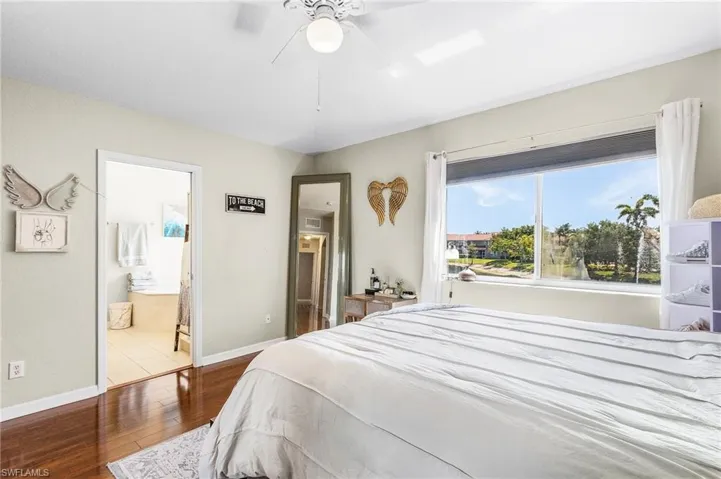 Bedroom with hardwood / wood-style floors, ensuite bath, baseboards, and ceiling fan