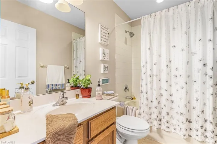 Bathroom featuring shower / tub combo with curtain, toilet, and vanity