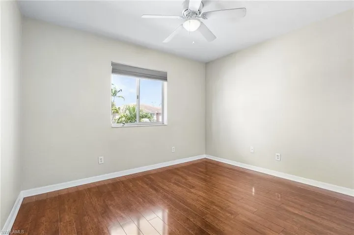 Empty room featuring wood finished floors, baseboards, and a ceiling fan