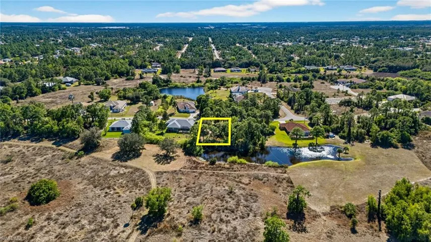 Aerial perspective of suburban area featuring property boundaries highlighted and a nearby body of water