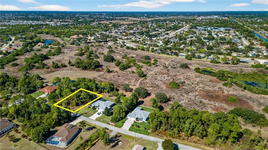 Aerial view of residential area with property boundaries highlighted and a large body of water