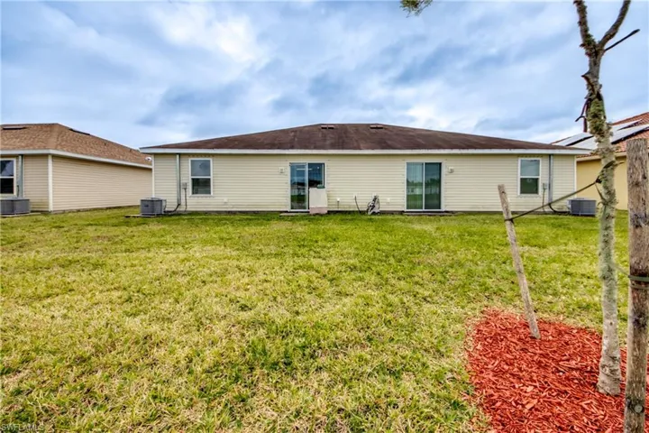 Rear view of house featuring a lawn and central AC