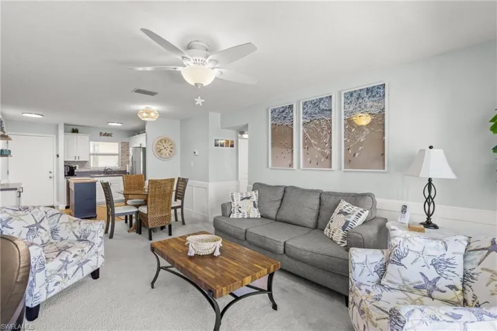 Living area with wainscoting, light carpet, and a ceiling fan