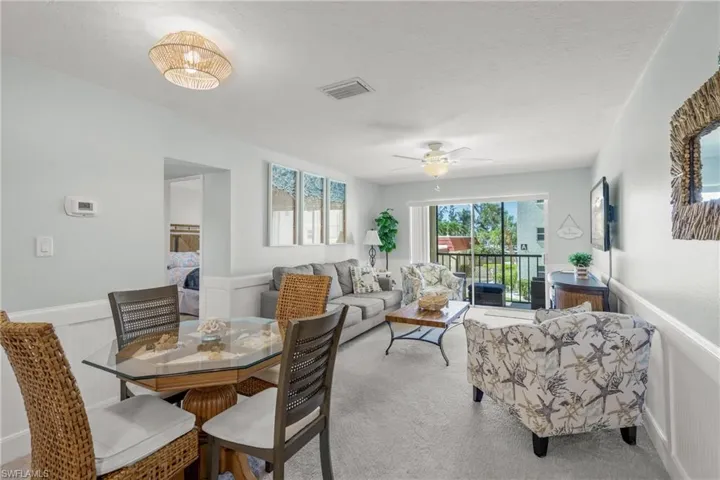 Carpeted dining space featuring a wainscoted wall, a ceiling fan, and a decorative wall