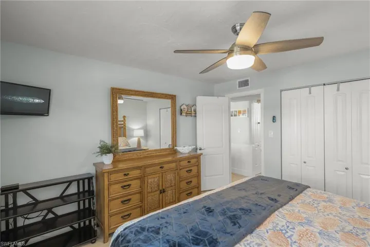 Bedroom with a ceiling fan, a closet, and light colored carpet