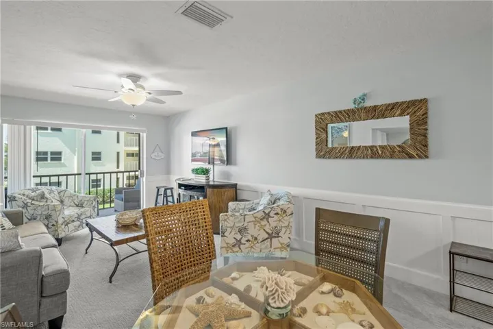 Dining room with a wainscoted wall, carpet flooring, a decorative wall, a ceiling fan, and a textured ceiling