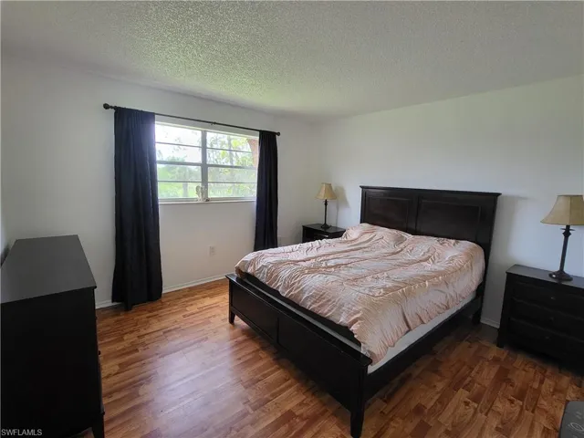 Bedroom 1 with wood-style flooring and a textured ceiling