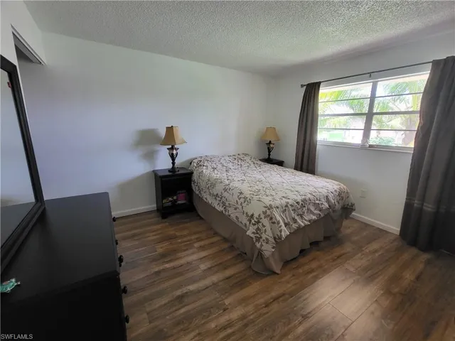 Bedroom 2 with a textured ceiling and dark wood-style floors