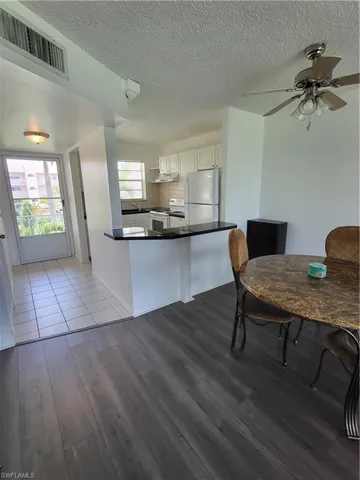 Kitchen with stove, white cabinets, kitchen peninsula, backsplash, and fridge