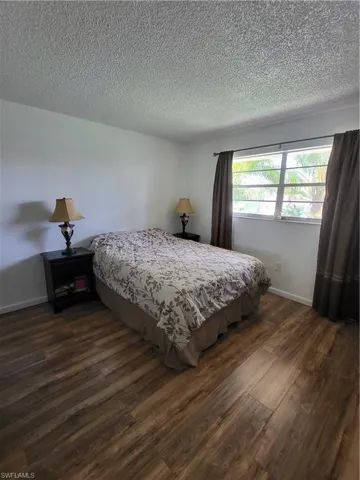 Bedroom 2 with a textured ceiling and dark wood-type flooring