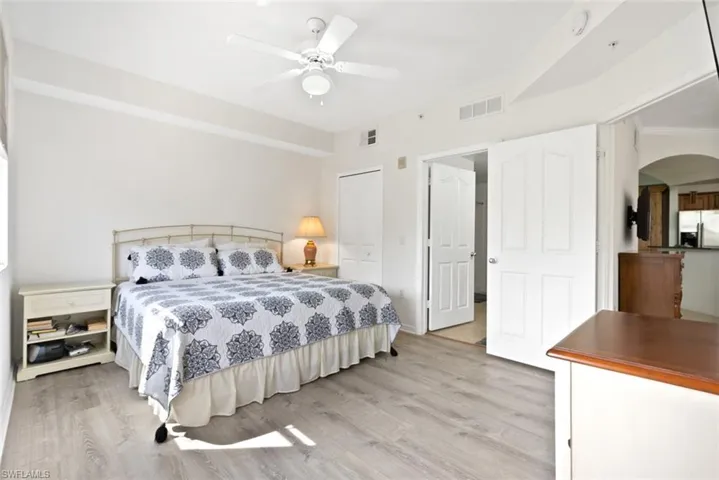 Bedroom featuring stainless steel fridge, light wood-type flooring, a closet, ceiling fan, and arched walkways