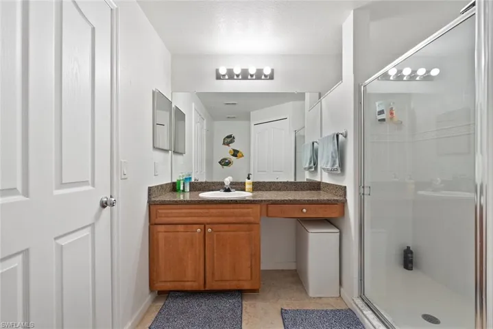 Full bathroom with vanity, light tile patterned flooring, and a shower stall