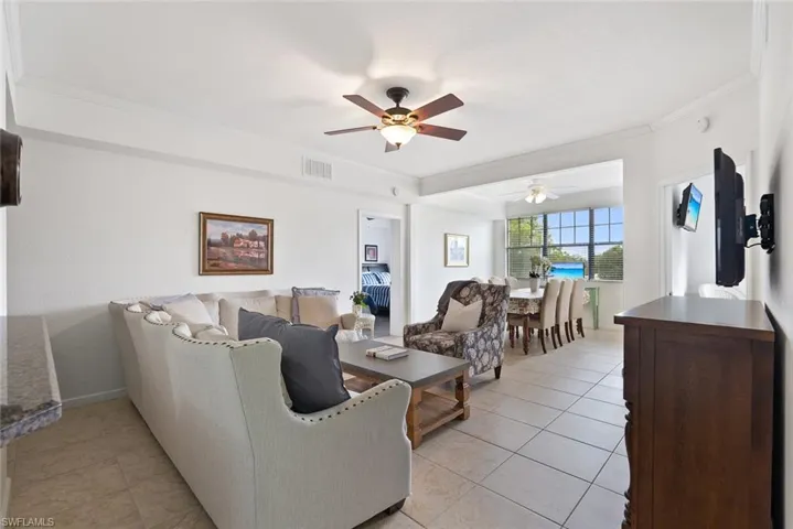 Living room with light tile patterned flooring, crown molding, and a ceiling fan