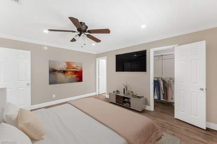 Bedroom featuring a walk in closet, wood finished floors, recessed lighting, crown molding, and a ceiling fan