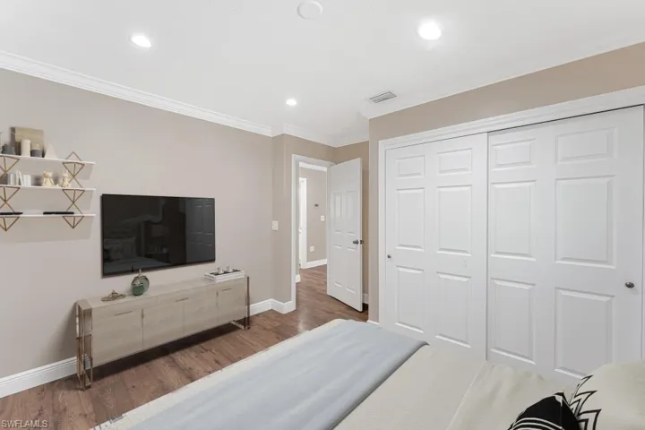 Bedroom featuring wood finished floors, crown molding, recessed lighting, and a closet