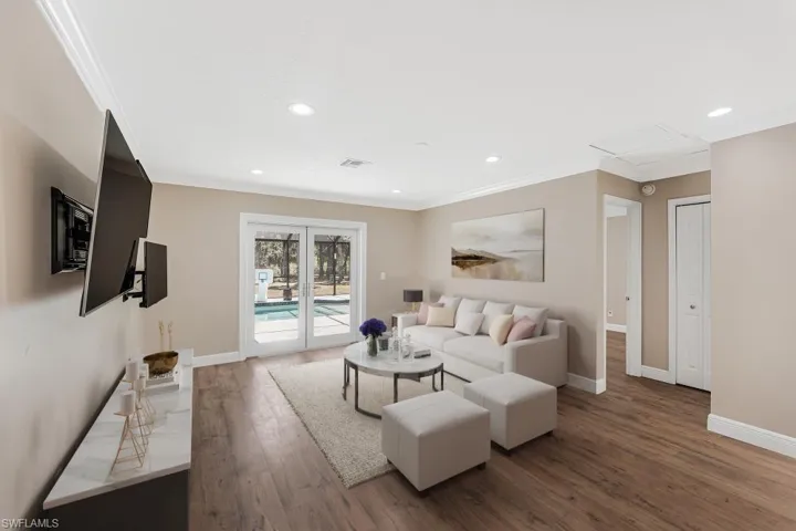 Living area with wood finished floors, ornamental molding, and recessed lighting