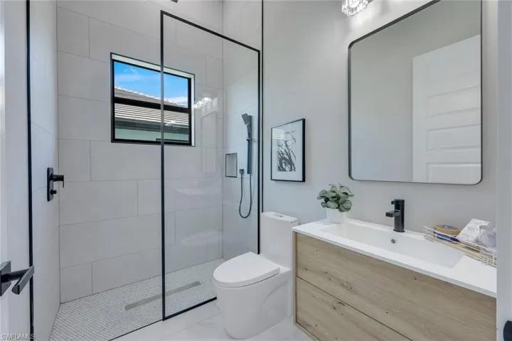 Bathroom featuring a shower stall, anity, toilet, and marble finish floor
