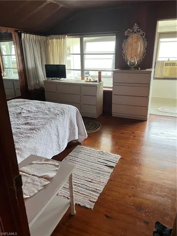 Bedroom with lofted ceiling, hardwood / wood-style floors, and multiple windows