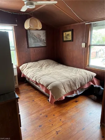 Bedroom featuring vaulted ceiling, wooden walls, and hardwood / wood-style floors