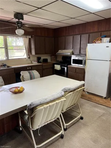 Kitchen featuring refrigerator, a paneled ceiling, stove, dark brown cabinets, and a ceiling fan