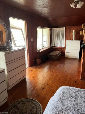 Bedroom featuring dark wood-type flooring, wood walls, and vaulted ceiling