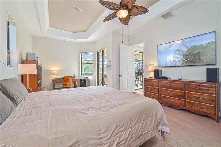 Carpeted bedroom featuring a raised ceiling, access to exterior, and ceiling fan