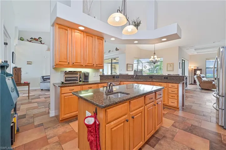 Kitchen featuring sink, hanging light fixtures, a high ceiling, kitchen peninsula, and a kitchen island with sink