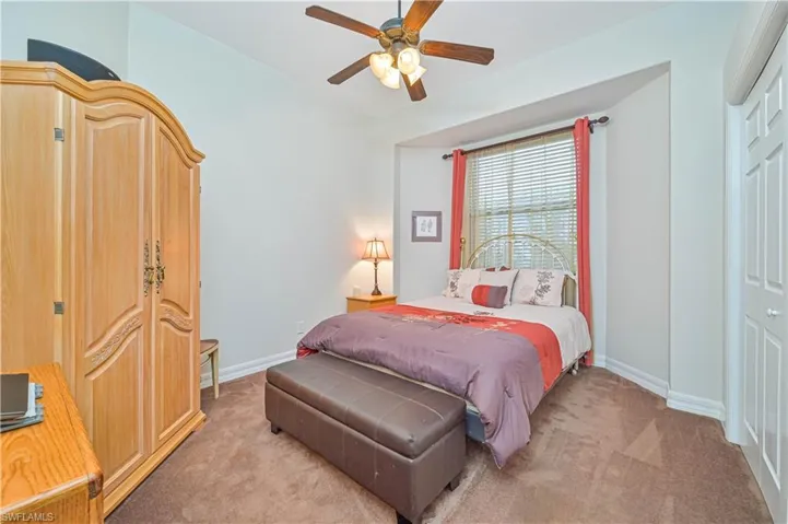 Carpeted bedroom with ceiling fan and a closet