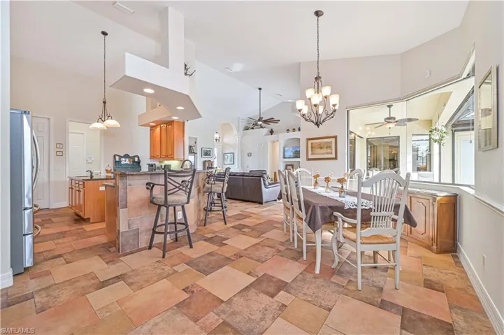 Dining area with ceiling fan with notable chandelier and high vaulted ceiling