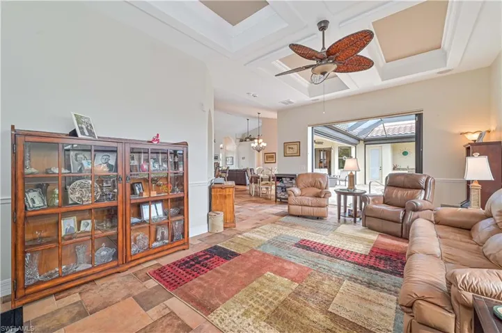Living room featuring beam ceiling, ceiling fan with notable chandelier, and coffered ceiling