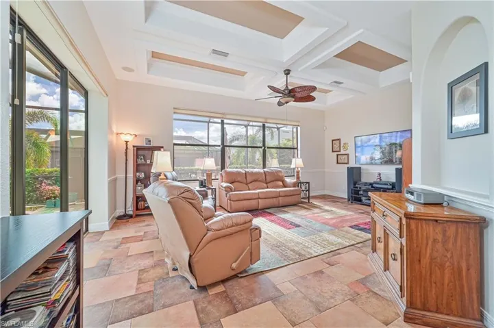 Living room featuring ceiling fan, beamed ceiling, a healthy amount of sunlight, and coffered ceiling