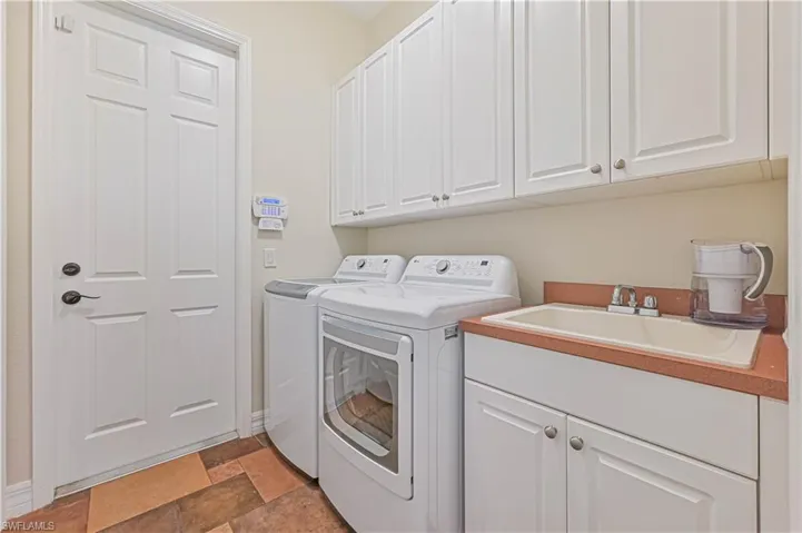 Washroom with washer and clothes dryer, cabinets, and sink