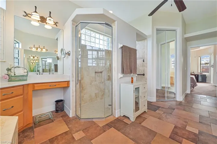 Bathroom featuring ceiling fan, vanity, and walk in shower