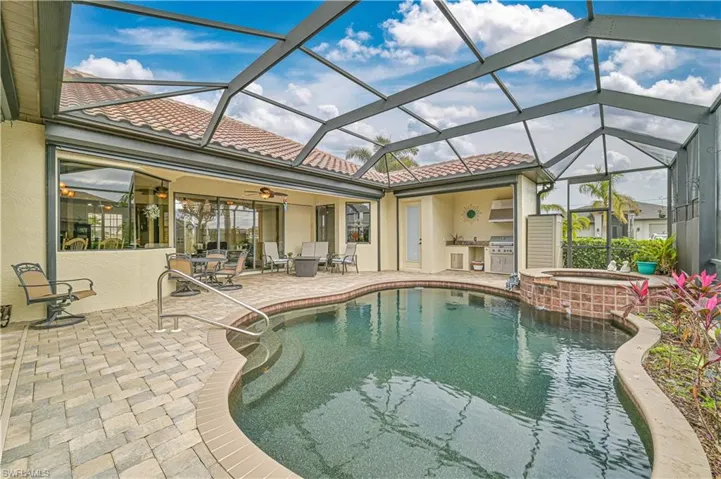 View of swimming pool featuring glass enclosure, grilling area, ceiling fan, an in ground hot tub, and a patio area