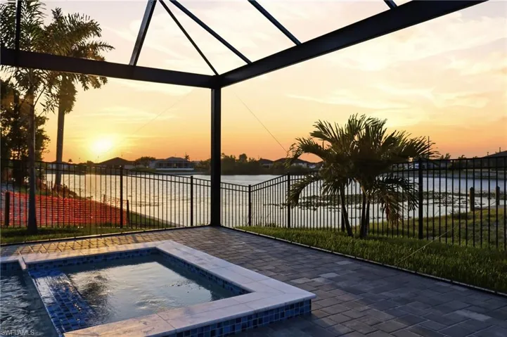 Enclosed outdoor living space featuring a screened lanai, integrated spa with mosaic tile, and paver decking